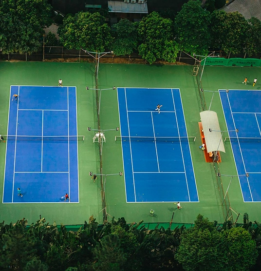 Aerial view of several blue tennis courts where players are in action.